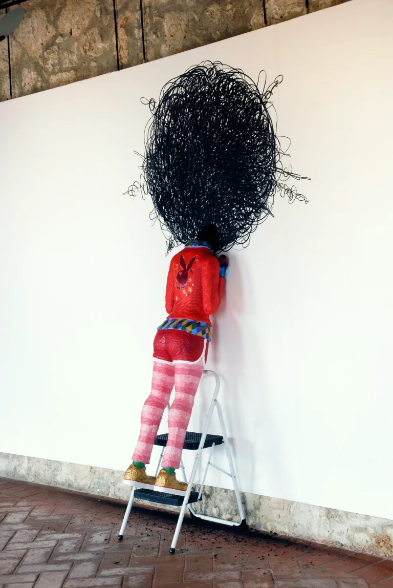 Afro, figura de una adolescente a tamaño real . tallada en madera policromada, Escalera y grafito sobre pared. 2009.